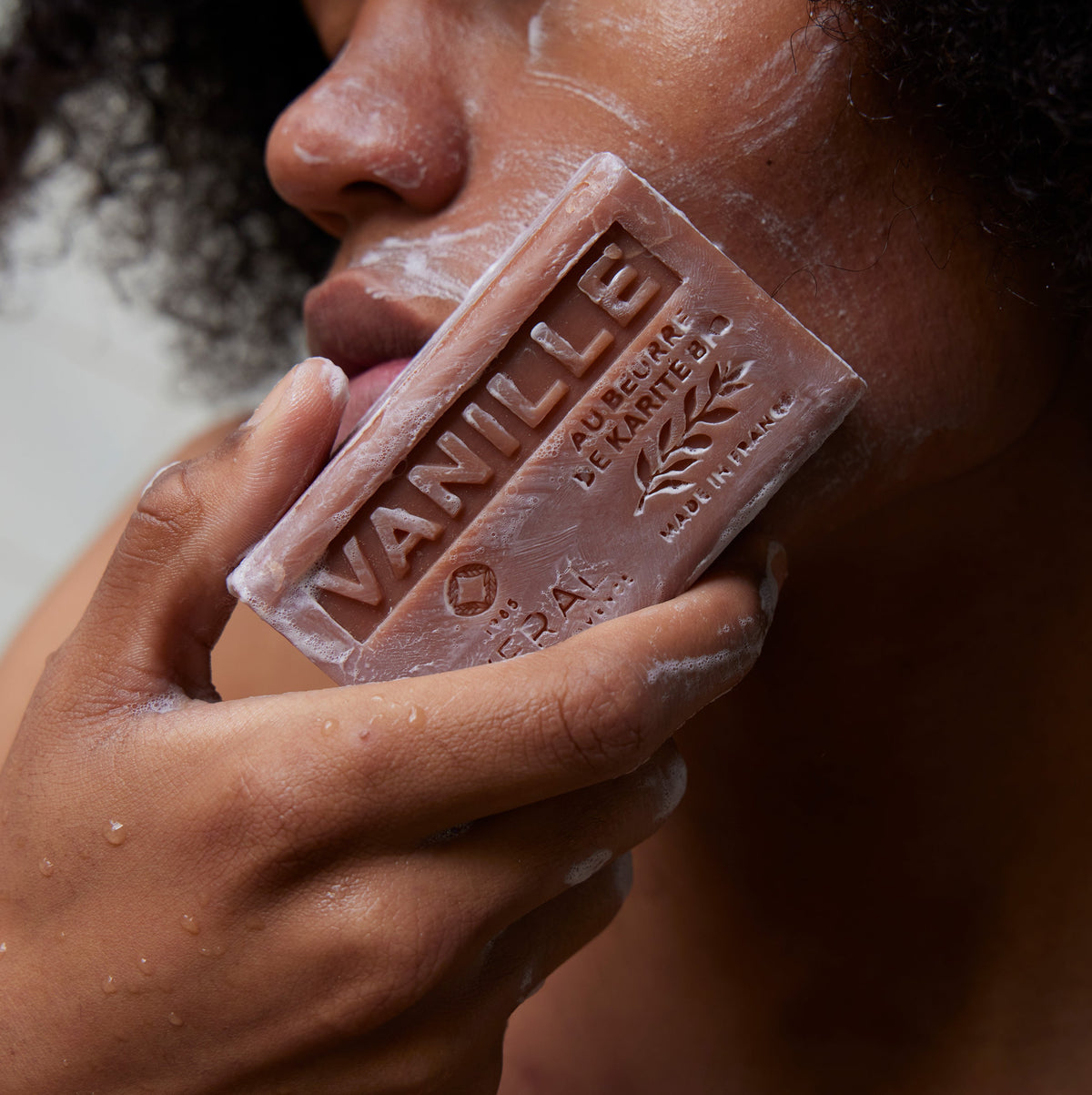 Woman holding an Averal Provence Vanilla French bar soap against her cheek