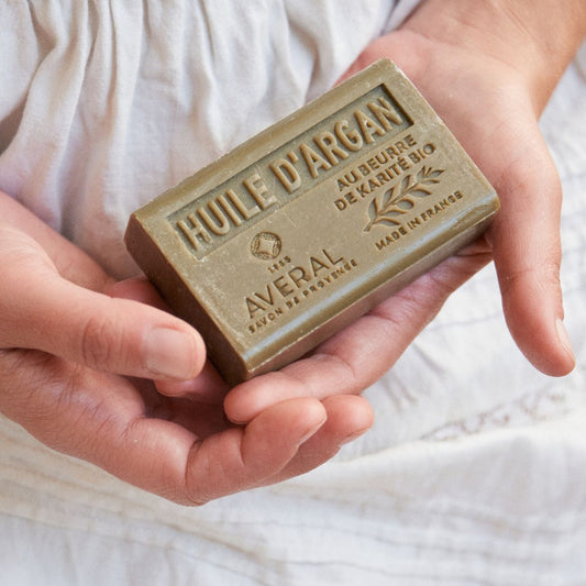 Averal Provence Argan Oil bar soap stamped Huile d'Argan held in two hands on white linen
