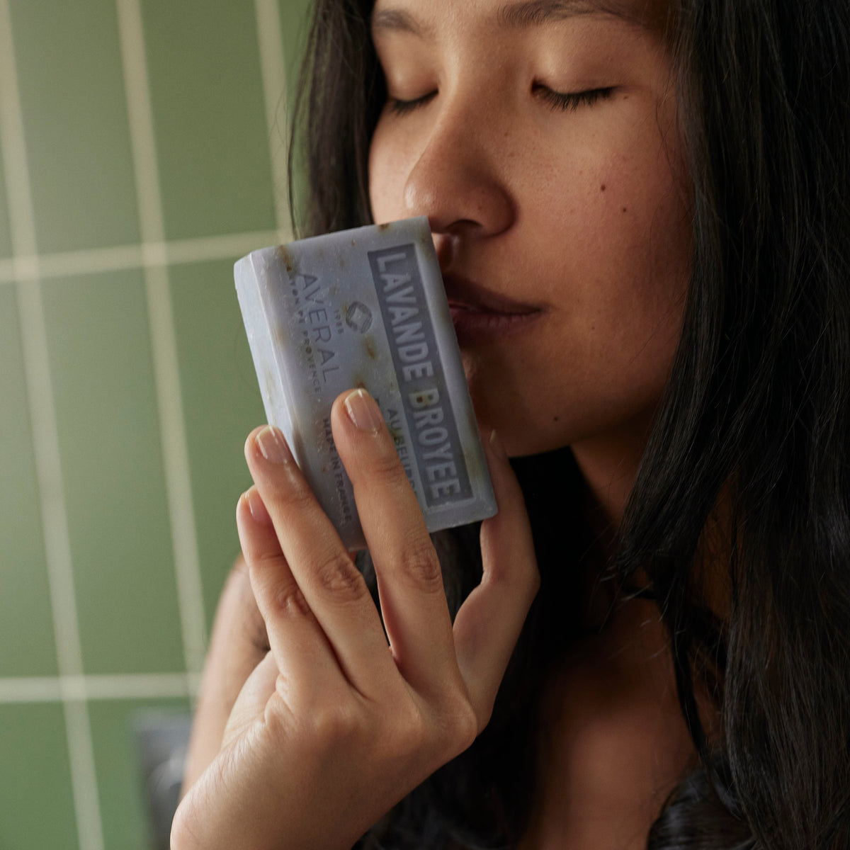 Woman with eyes closed smelling an Averal Provence Crushed Lavender French bar soap