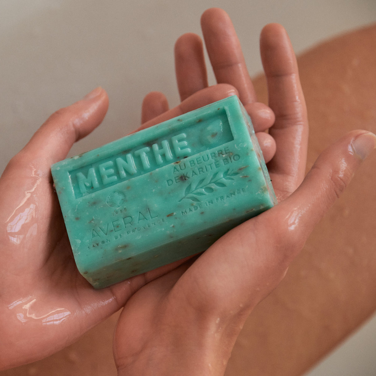 Wet hands cupping a speckled green Averal Provence Mint French bar soap