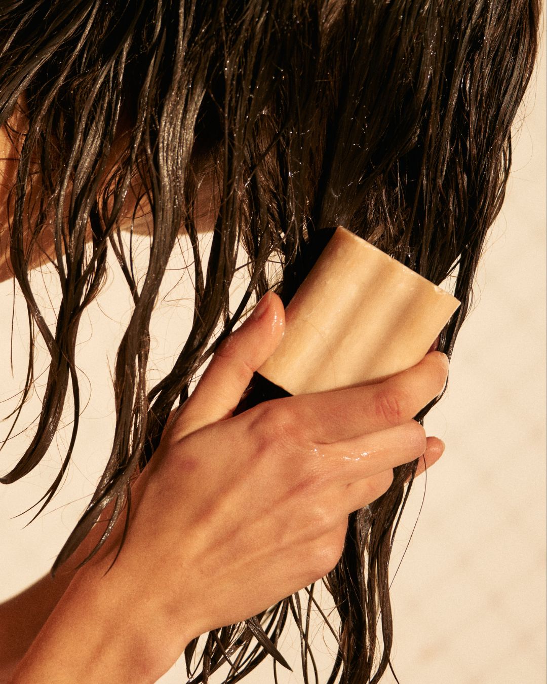 Solid shampoo bar smoothed through wet hair